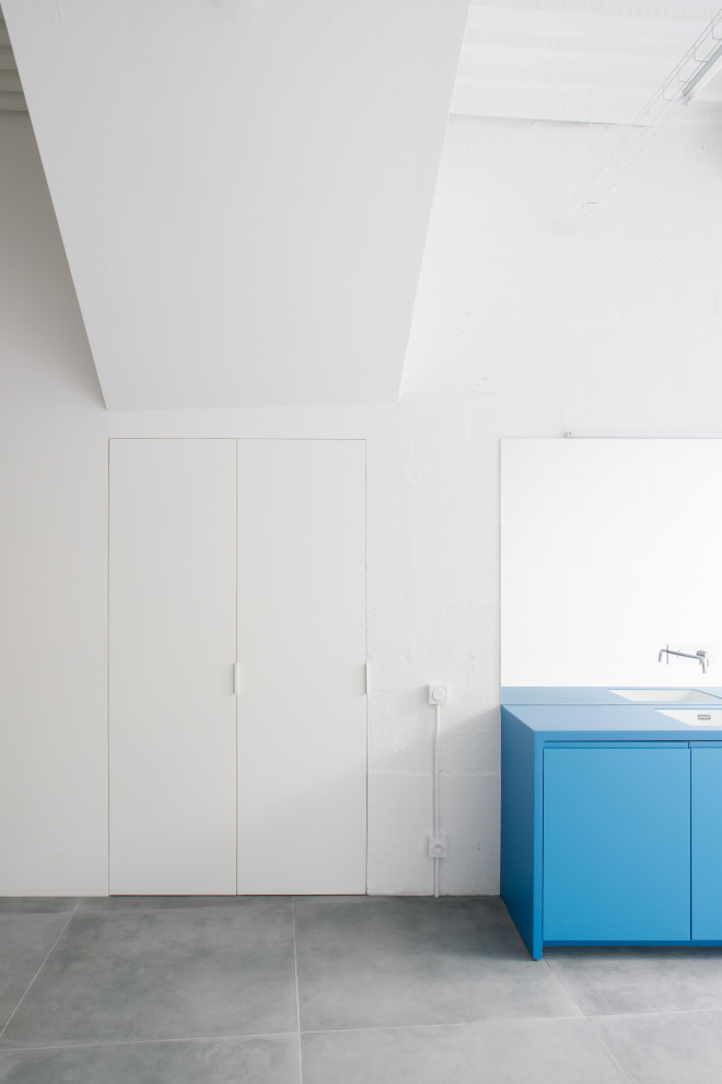 Источник вдохновения для домашнего уюта: прямая, серо-белая кухня-гостиная среднего размера в стиле модернизм с врезной мойкой, плоскими фасадами, синими фасадами, столешницей из акрилового камня, зеркальным фартуком, техникой под мебельный фасад, полом из керамической плитки, серым полом, синей столешницей и балками на потолке