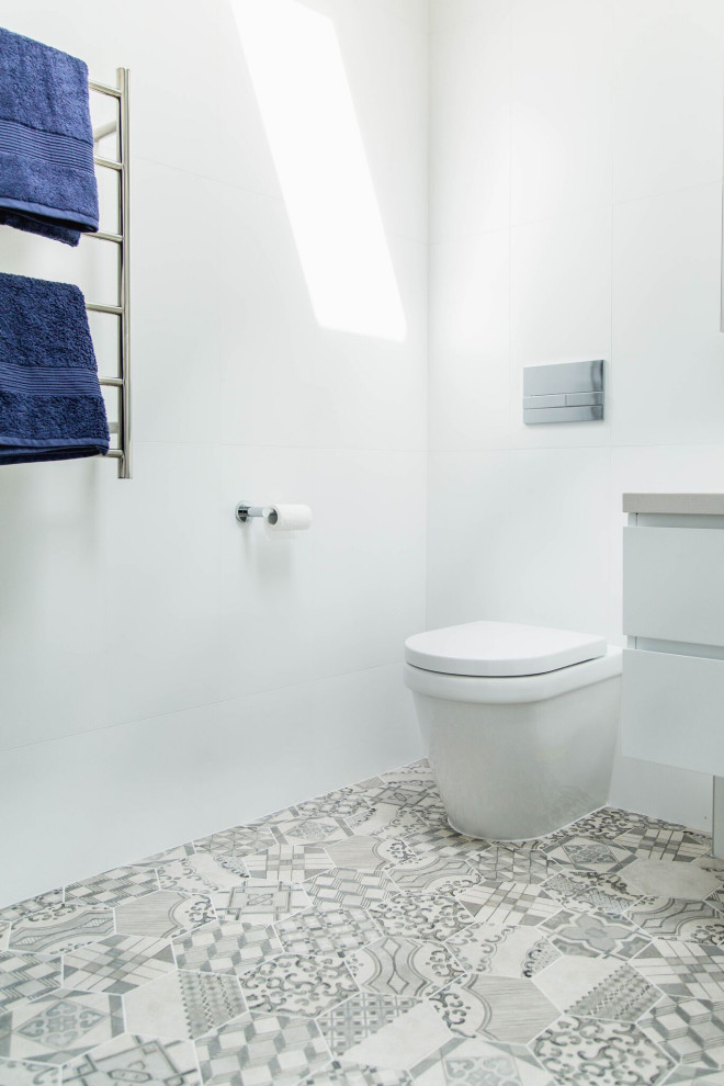 Design ideas for a mid-sized transitional master bathroom in Melbourne with flat-panel cabinets, white cabinets, a curbless shower, a wall-mount toilet, white tile, porcelain tile, white walls, porcelain floors, a vessel sink, engineered quartz benchtops, grey floor, an open shower and multi-coloured benchtops.