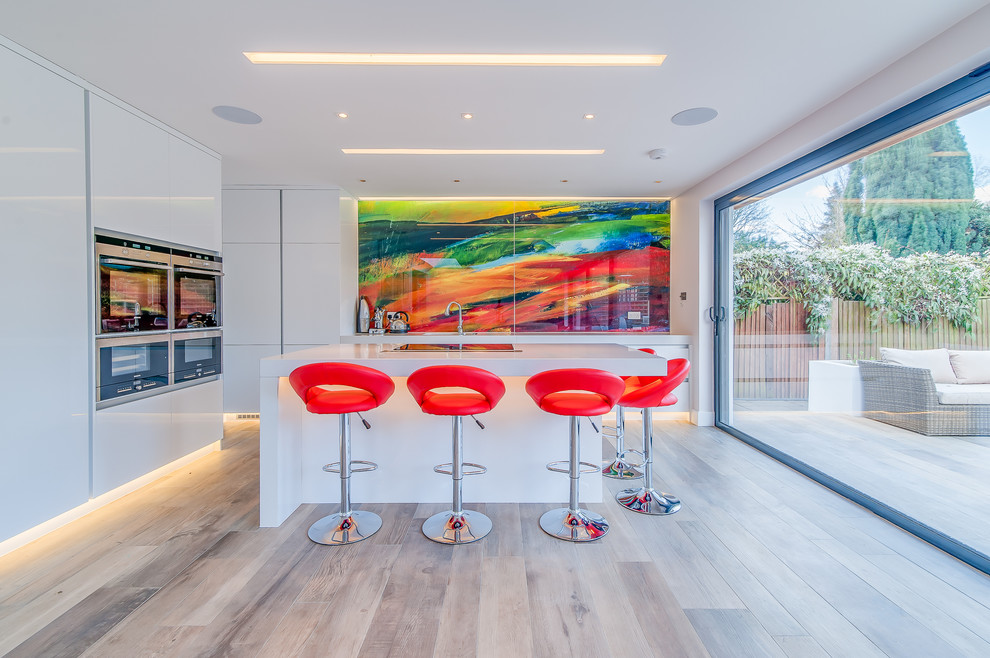 Photo of a mid-sized contemporary eat-in kitchen in Surrey with an undermount sink, flat-panel cabinets, white cabinets, quartzite benchtops, multi-coloured splashback, glass sheet splashback, stainless steel appliances, porcelain floors and with island.