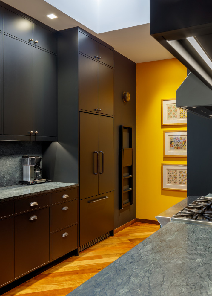 This is an example of a small contemporary galley kitchen/diner in Seattle with an integrated sink, beaded cabinets, black cabinets, soapstone worktops, grey splashback, stone slab splashback, black appliances, medium hardwood flooring, no island, brown floors and grey worktops.