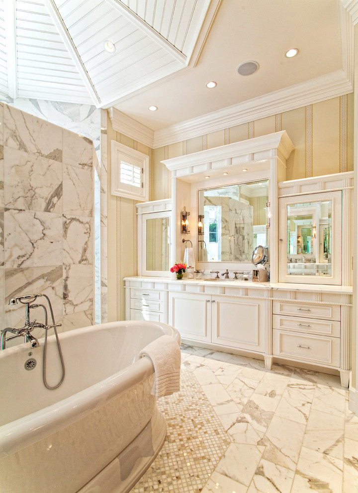 Photo of a large tropical master bathroom in Miami with recessed-panel cabinets, white cabinets, a freestanding tub, white tile and multi-coloured walls.