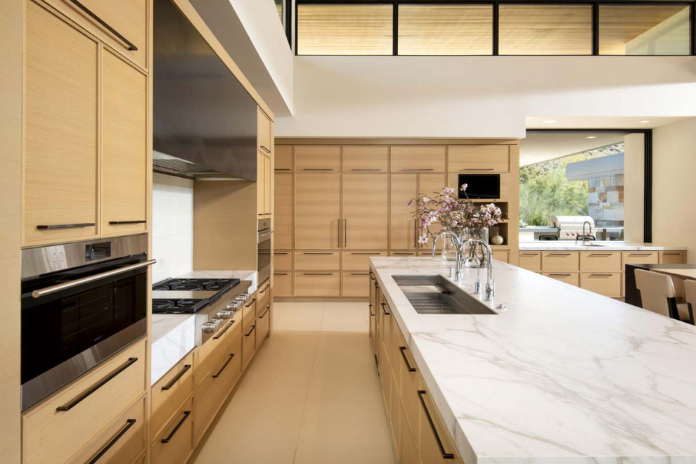 Design ideas for an expansive contemporary l-shaped open plan kitchen in Phoenix with an undermount sink, flat-panel cabinets, medium wood cabinets, marble benchtops, white splashback, ceramic splashback, stainless steel appliances, with island, beige floor, white benchtop and wood.