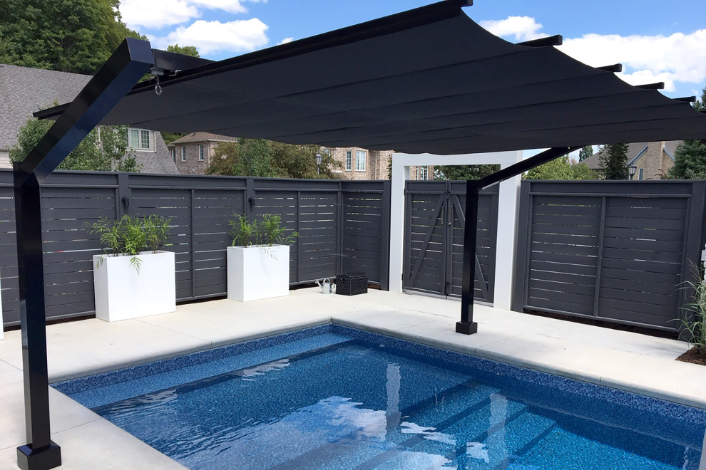 This is an example of a large modern side yard rectangular lap pool in Toronto with tile.