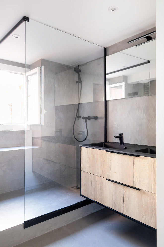 Small industrial master bathroom in Lyon with beaded inset cabinets, light wood cabinets, an open shower, a two-piece toilet, grey walls, concrete floors, a wall-mount sink, granite benchtops, grey floor, black benchtops, a double vanity and a floating vanity.