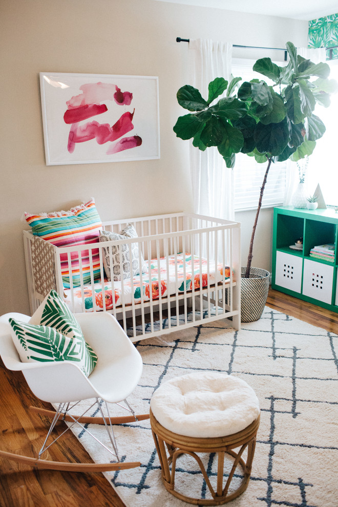Inspiration for a mid-sized eclectic nursery for girls in Orange County with beige walls and medium hardwood floors.