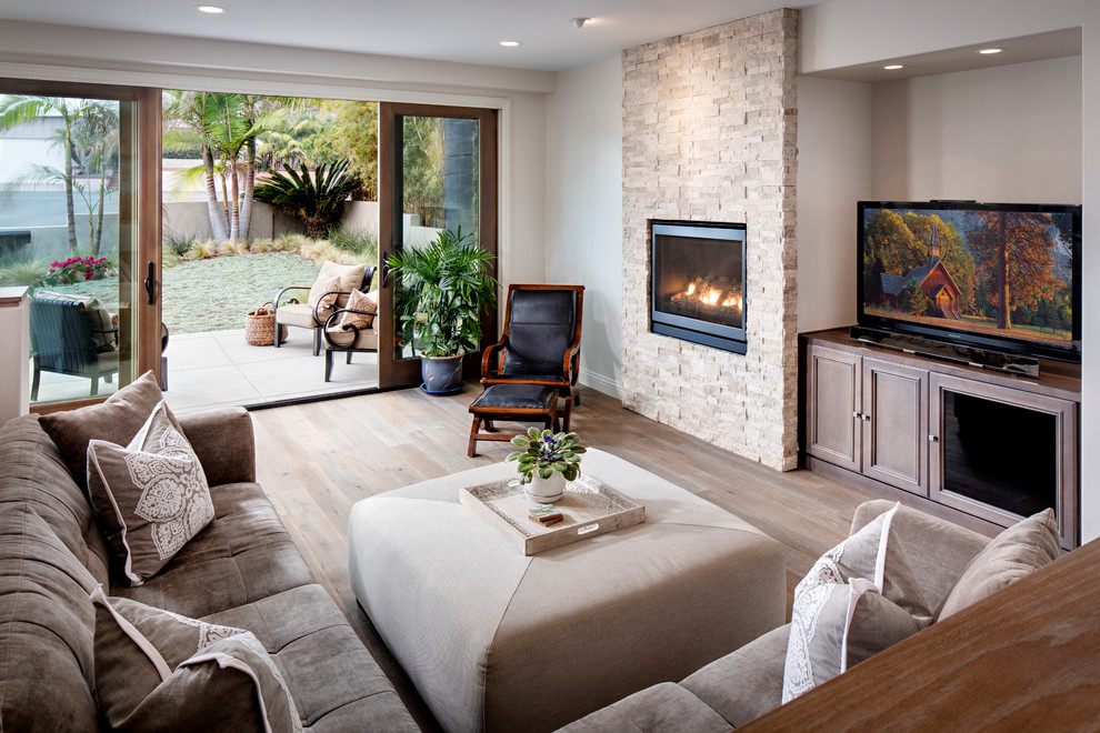 Inspiration for a large contemporary open concept living room in San Diego with beige walls, light hardwood floors, a hanging fireplace, a stone fireplace surround and a built-in media wall.
