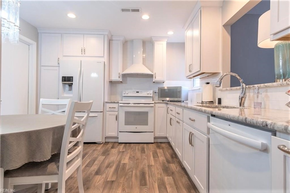Eat-in kitchen - mid-sized transitional l-shaped vinyl floor and brown floor eat-in kitchen idea with an undermount sink, shaker cabinets, white cabinets, granite countertops, white backsplash, ceramic backsplash, white appliances, no island and gray countertops