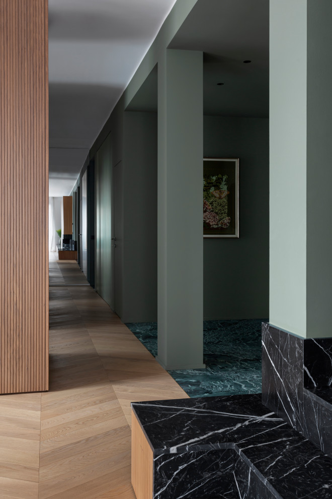 Großer Moderner Flur mit grüner Wandfarbe, braunem Holzboden und vertäfelten Wänden in Mailand