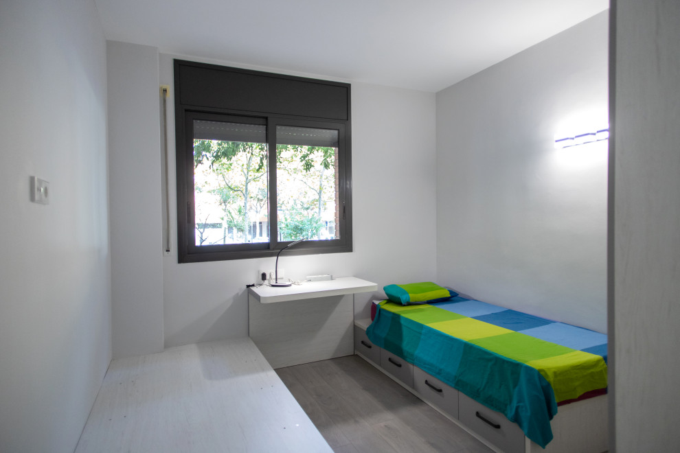 This is an example of a mid-sized contemporary guest bedroom in Barcelona with beige walls, medium hardwood floors, no fireplace and brown floor.