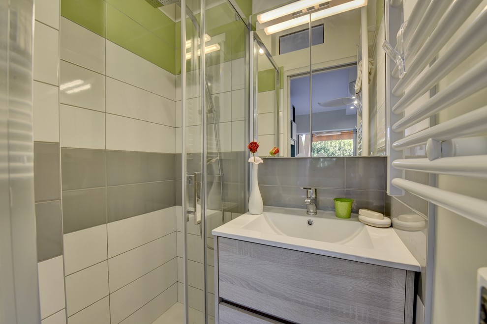 Small contemporary 3/4 bathroom in Toulouse with beaded inset cabinets, light wood cabinets, a curbless shower, a wall-mount toilet, multi-coloured tile, ceramic tile, white walls, ceramic floors, a console sink, solid surface benchtops, beige floor, a sliding shower screen and white benchtops.