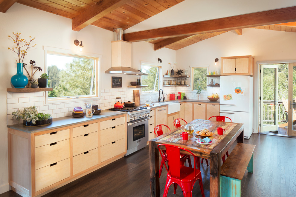 Design ideas for a mid-sized country u-shaped eat-in kitchen in San Francisco with a farmhouse sink, light wood cabinets, concrete benchtops, white splashback, stainless steel appliances, dark hardwood floors, flat-panel cabinets and subway tile splashback.