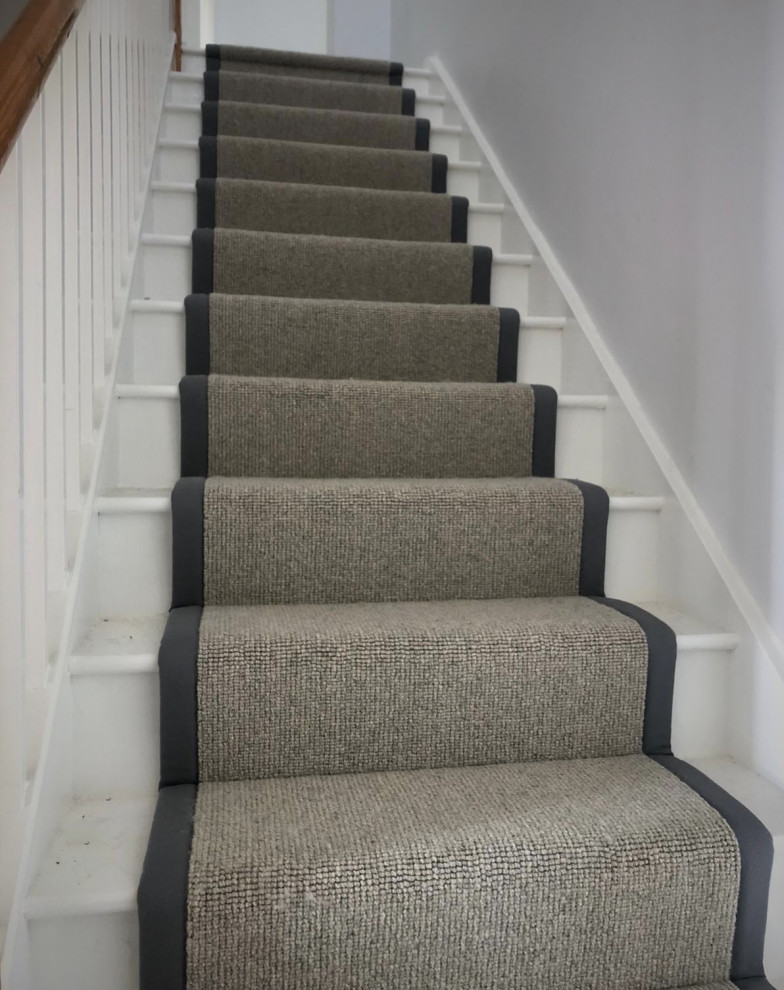 Modern carpeted staircase in Hertfordshire with carpet risers and wood railing.