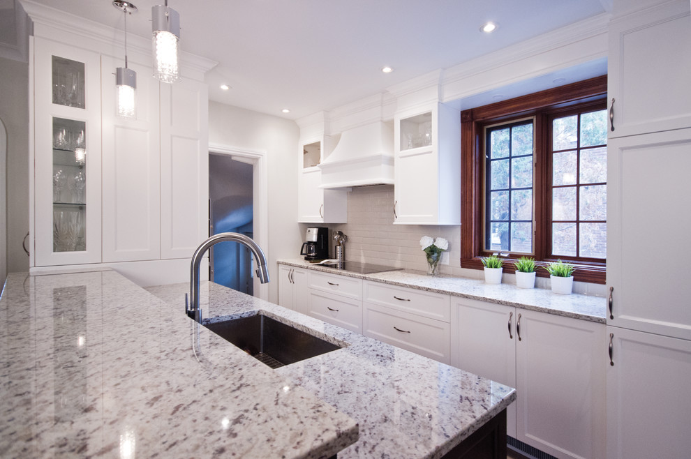 Example of a mid-sized transitional galley ceramic tile eat-in kitchen design in Montreal with an undermount sink, shaker cabinets, white cabinets, granite countertops, beige backsplash, subway tile backsplash, stainless steel appliances and an island