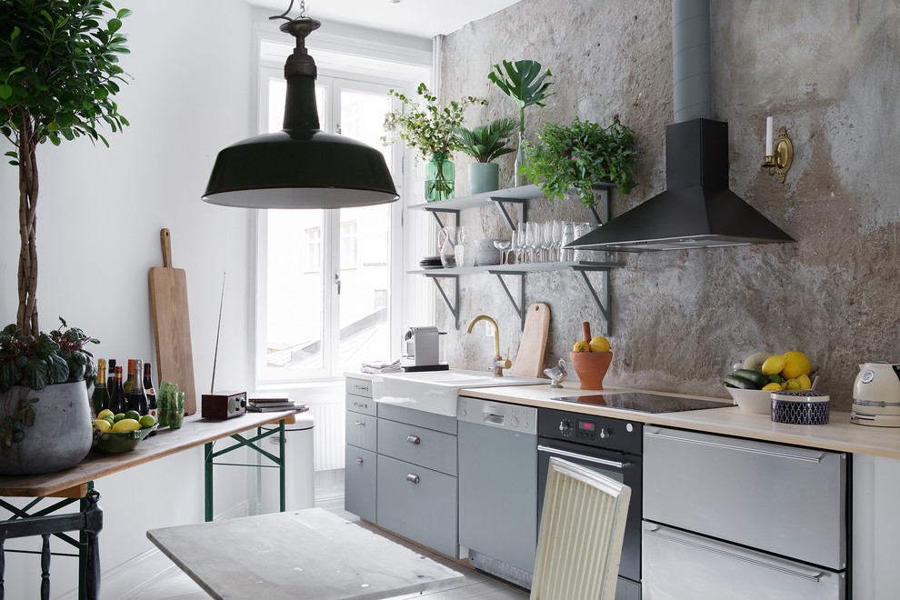 Small industrial single-wall eat-in kitchen in Stockholm with flat-panel cabinets, grey cabinets, wood benchtops and no island.