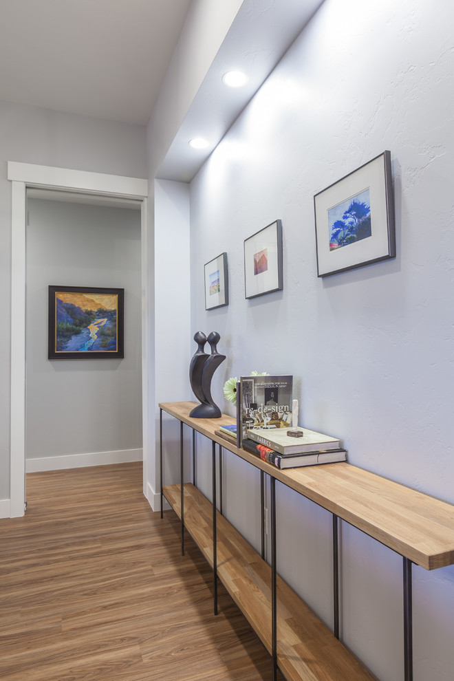 Photo of a mid-sized contemporary hallway in Denver with blue walls, medium hardwood floors and brown floor.