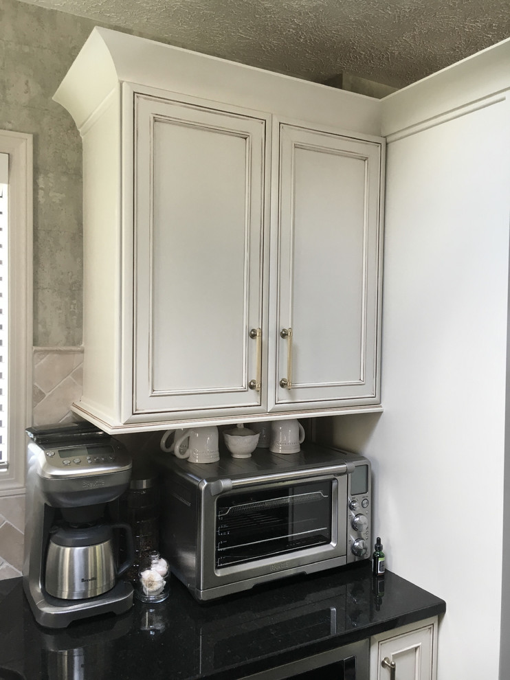 Inspiration for a large transitional u-shaped laminate floor and gray floor eat-in kitchen remodel with an undermount sink, recessed-panel cabinets, white cabinets, granite countertops, white backsplash, ceramic backsplash, stainless steel appliances, an island and black countertops