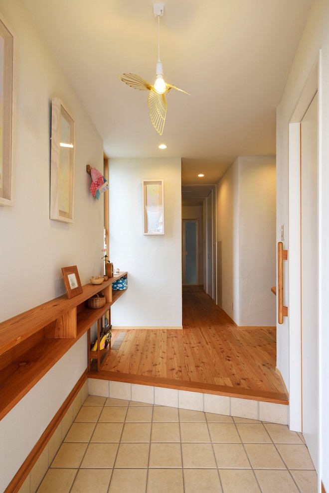 Inspiration for a mid-sized asian entry hall in Tokyo Suburbs with white walls, medium hardwood floors, a sliding front door, a medium wood front door and brown floor.