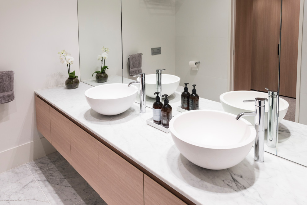 Photo of a mid-sized contemporary master bathroom in Melbourne with recessed-panel cabinets, light wood cabinets, an alcove shower, a one-piece toilet, mirror tile, yellow walls, marble floors, a vessel sink, marble benchtops, white floor, an open shower and white benchtops.