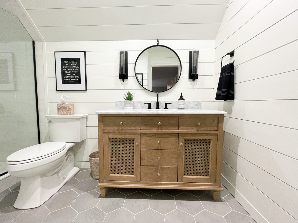 This is an example of a medium sized country family bathroom in Detroit with medium wood cabinets, an alcove shower, a two-piece toilet, white tiles, white walls, porcelain flooring, a submerged sink, marble worktops, grey floors, a hinged door, a wall niche, a single sink, a freestanding vanity unit, a timber clad ceiling, tongue and groove walls, recessed-panel cabinets, porcelain tiles and grey worktops.
