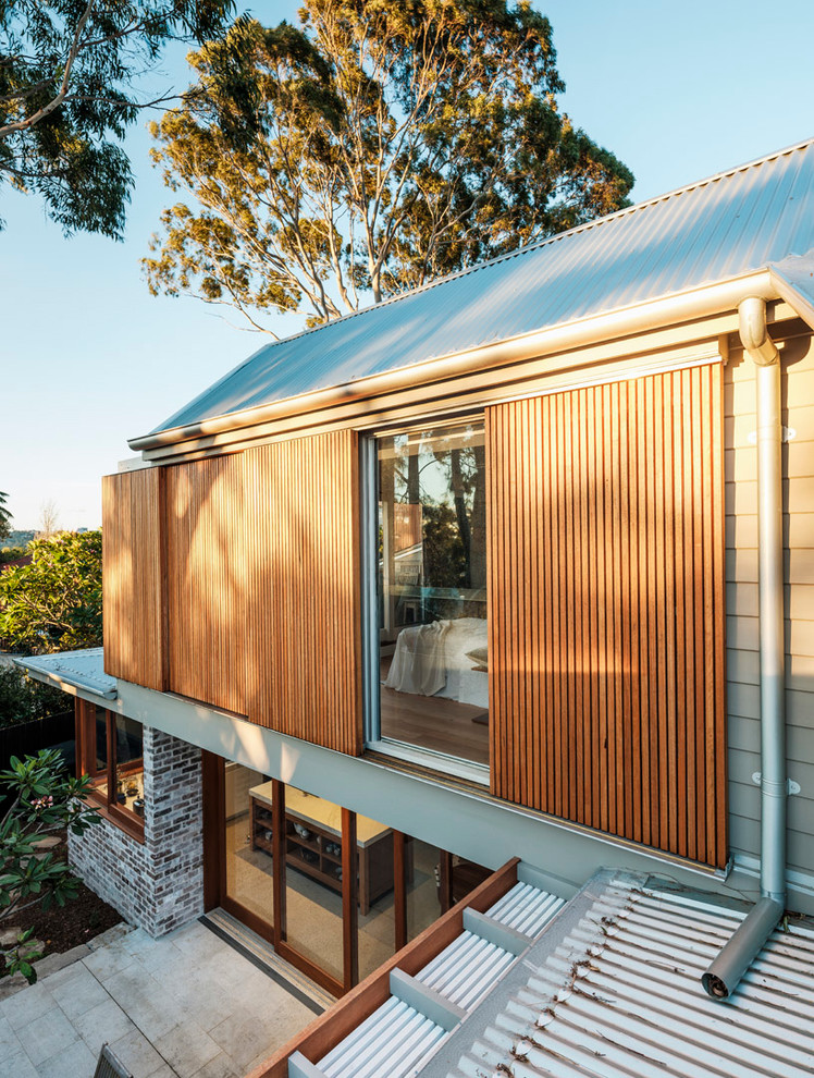 Inspiration for a mid-sized contemporary two-storey beige house exterior in Sydney with wood siding, a hip roof and a metal roof.