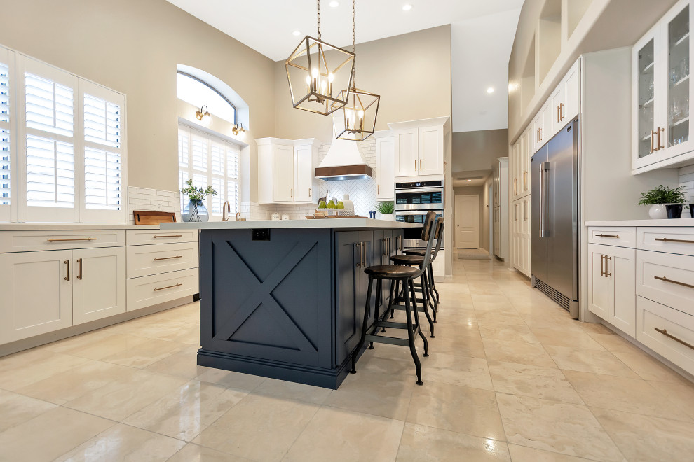 Inspiration for a large transitional u-shaped open concept kitchen remodel in Phoenix with a farmhouse sink, shaker cabinets, white cabinets, quartz countertops, white backsplash, subway tile backsplash, stainless steel appliances, an island and white countertops