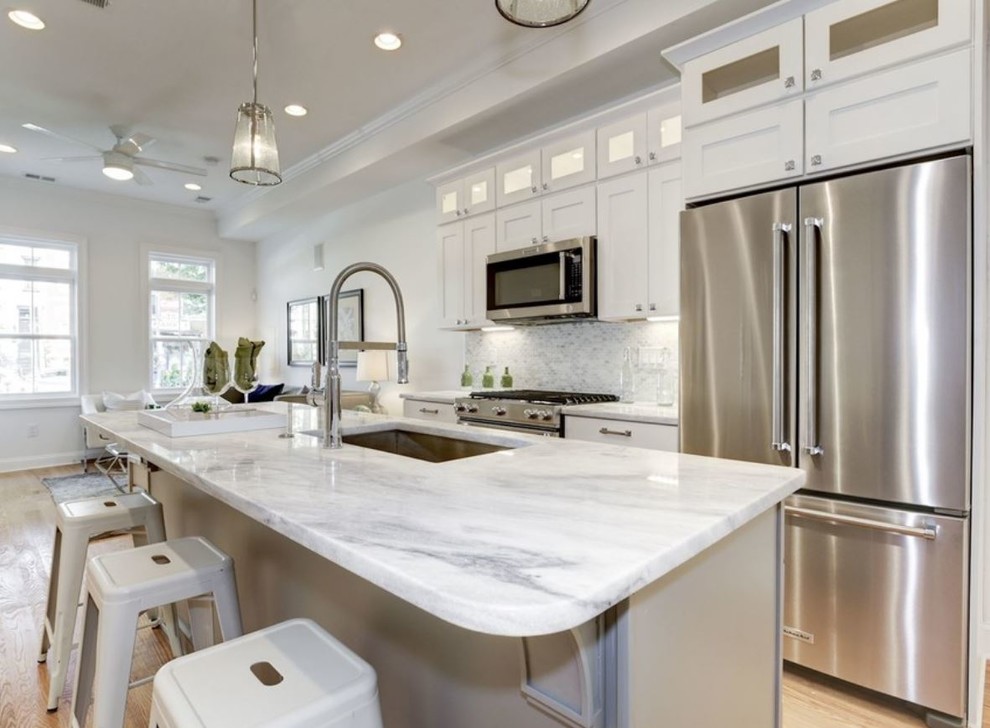 Inspiration for a large transitional single-wall dark wood floor and brown floor eat-in kitchen remodel with an undermount sink, shaker cabinets, white cabinets, marble countertops, gray backsplash, marble backsplash, stainless steel appliances and an island