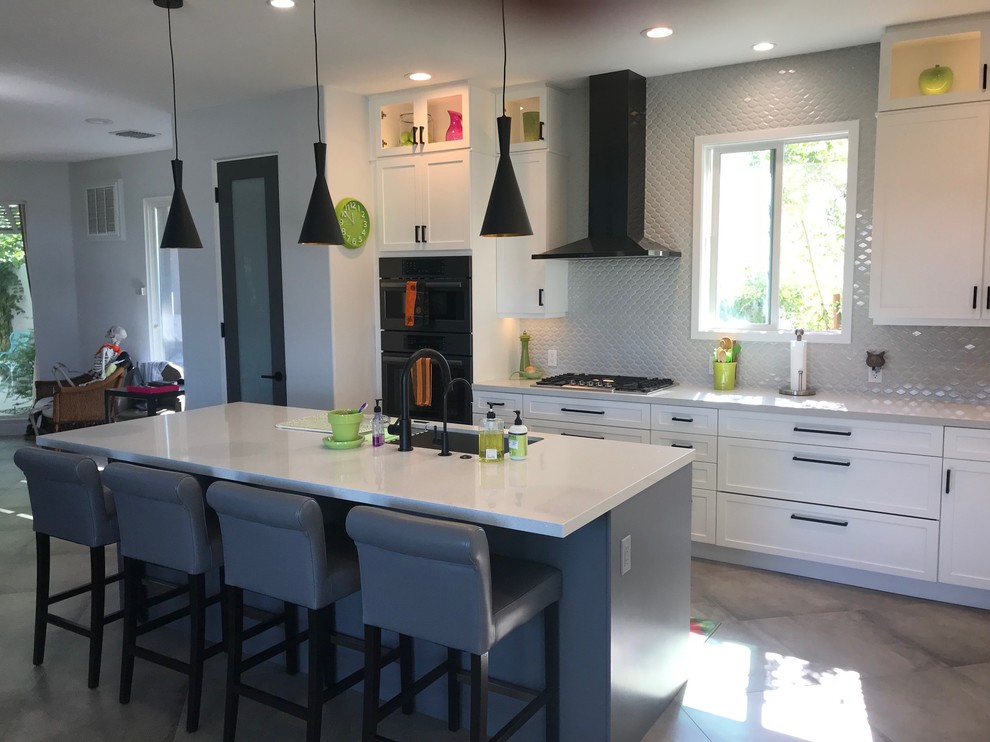 Photo of a large contemporary eat-in kitchen in Other with shaker cabinets, white cabinets, quartzite benchtops, white splashback, ceramic splashback, porcelain floors, with island, grey floor, grey benchtop, a drop-in sink and black appliances.