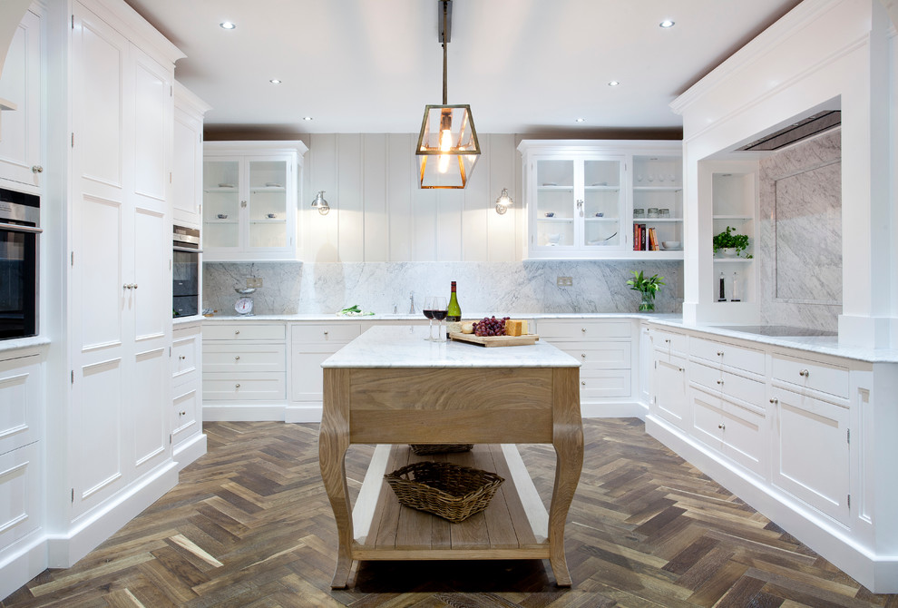 Design ideas for a large eclectic u-shaped kitchen in Dublin with an integrated sink, beaded inset cabinets, white cabinets, marble benchtops, white splashback, stone slab splashback, stainless steel appliances, dark hardwood floors and with island.
