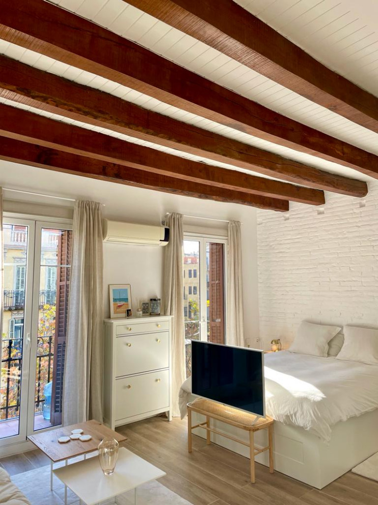 Ejemplo de dormitorio tipo loft y blanco y madera rústico pequeño con paredes blancas, suelo de baldosas de cerámica, suelo marrón, vigas vistas, ladrillo y con escritorio