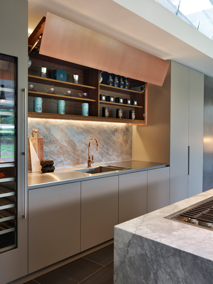 Inspiration for an expansive contemporary single-wall open plan kitchen in London with flat-panel cabinets, beige cabinets, marble benchtops, beige splashback, panelled appliances, ceramic floors, with island, black floor, grey benchtop and stone slab splashback.