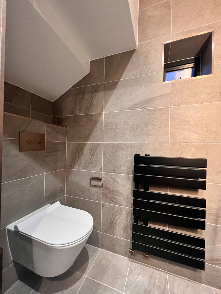 Design ideas for a medium sized contemporary bathroom with flat-panel cabinets, beige cabinets, a wall mounted toilet, porcelain tiles, brown walls, porcelain flooring, a built-in sink, beige floors, an open shower, a feature wall, a single sink and a floating vanity unit.