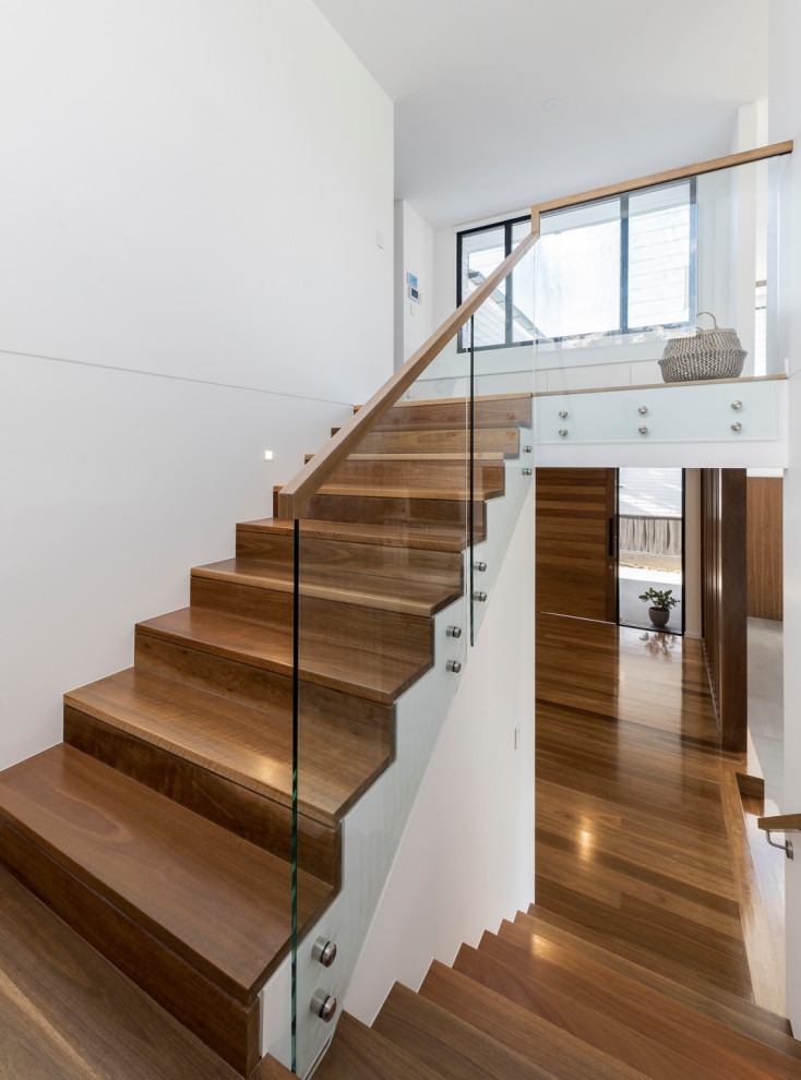 Photo of a contemporary wood u-shaped staircase with wood risers and glass railing.