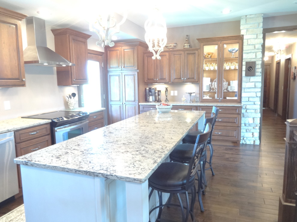 Inspiration for a large single-wall open concept kitchen remodel with an undermount sink, raised-panel cabinets, medium tone wood cabinets, quartzite countertops, stainless steel appliances and an island