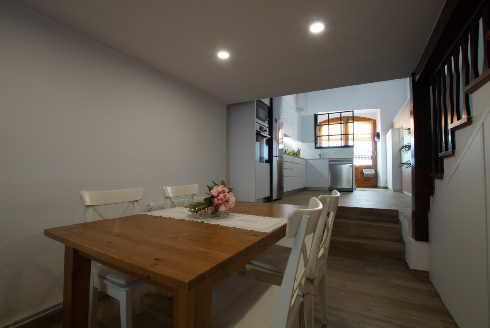 Medium sized kitchen/dining room in Barcelona with white walls, medium hardwood flooring and brown floors.