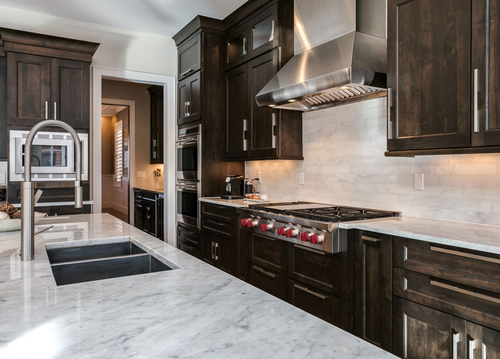 Foto di una cucina abitabile classica di medie dimensioni con lavello sottopiano, elettrodomestici in acciaio inossidabile e pavimento in legno massello medio