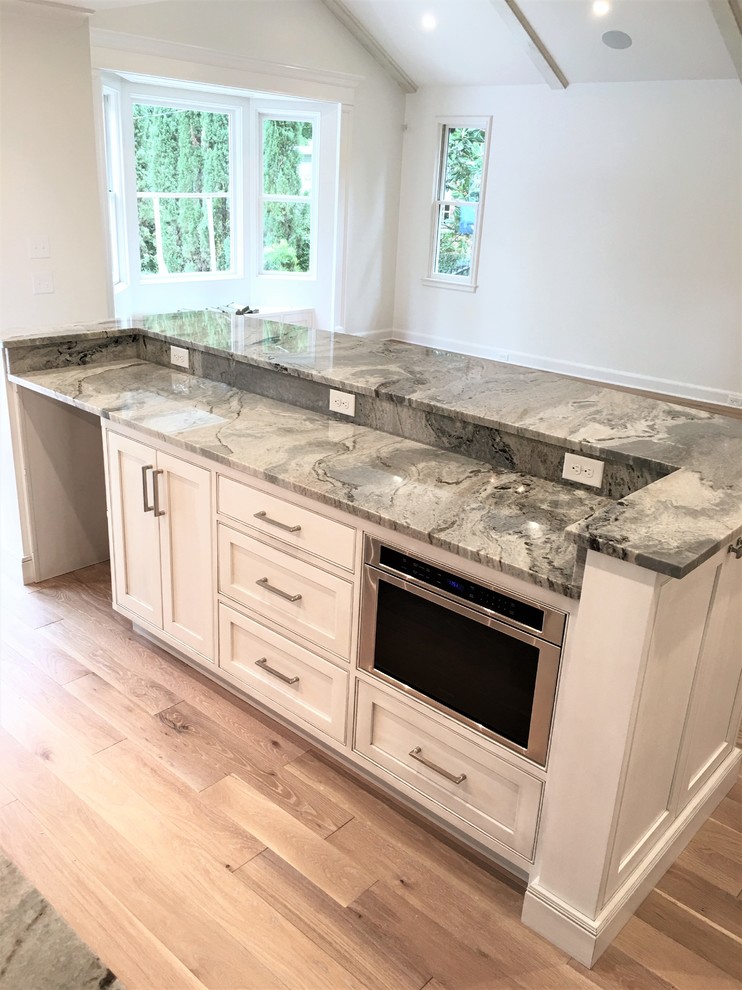 Large transitional l-shaped medium tone wood floor and brown floor eat-in kitchen photo with an undermount sink, flat-panel cabinets, gray cabinets, marble countertops, gray backsplash, marble backsplash, paneled appliances and an island