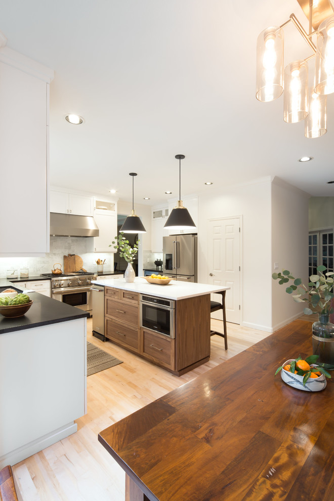 Example of a mid-sized transitional l-shaped light wood floor and brown floor eat-in kitchen design in Seattle with an undermount sink, shaker cabinets, white cabinets, quartz countertops, multicolored backsplash, marble backsplash, stainless steel appliances and an island