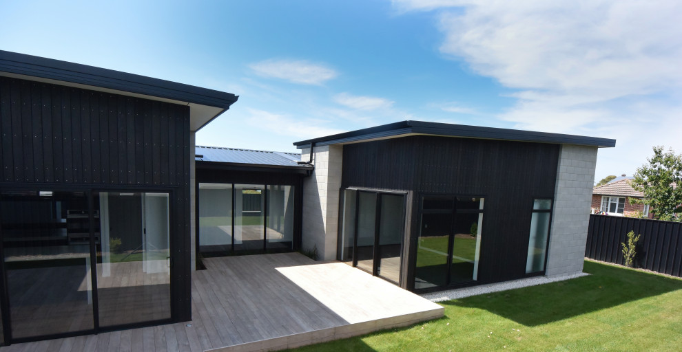 На фото: черный дом в стиле модернизм с облицовкой из бетона и черной крышей с