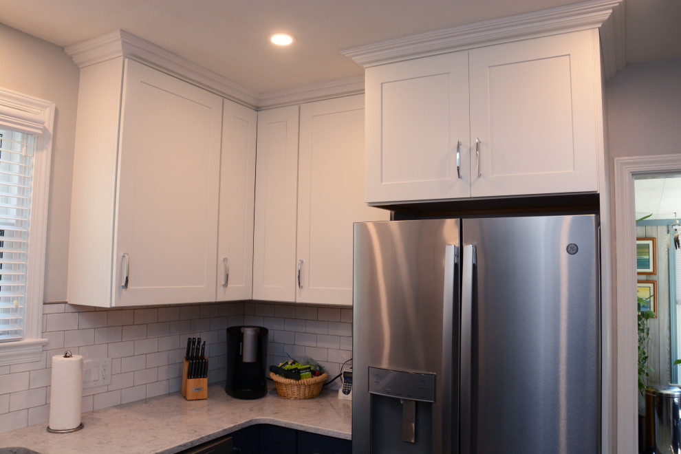 Design ideas for a small transitional u-shaped separate kitchen in Baltimore with an undermount sink, recessed-panel cabinets, white cabinets, quartz benchtops, white splashback, subway tile splashback, stainless steel appliances, no island, grey floor and white benchtop.