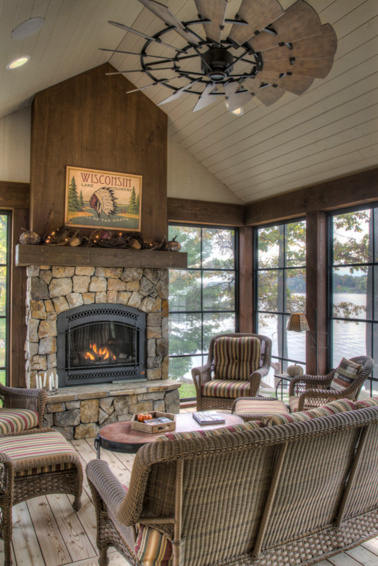 Photo of a mid-sized country sunroom in Minneapolis with medium hardwood floors, a standard fireplace, a stone fireplace surround, a standard ceiling and brown floor.