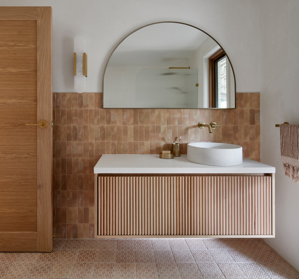 This is an example of a mid-sized modern master bathroom in Melbourne with an open shower, a two-piece toilet, pink tile, porcelain tile, white walls, porcelain floors, pink floor, an open shower, white benchtops, a single vanity, a floating vanity, medium wood cabinets and flat-panel cabinets.