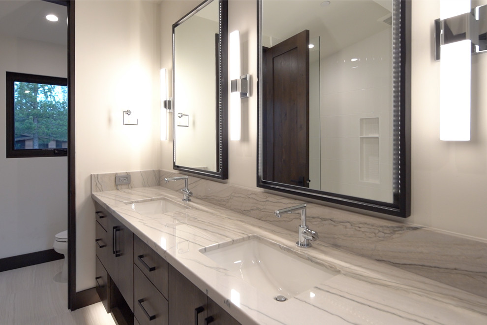 Modern inredning av ett stort grå grått en-suite badrum, med släta luckor, skåp i mellenmörkt trä, ett fristående badkar, en öppen dusch, en toalettstol med separat cisternkåpa, vit kakel, vita väggar, klinkergolv i porslin, ett undermonterad handfat, bänkskiva i kvartsit, grått golv och med dusch som är öppen