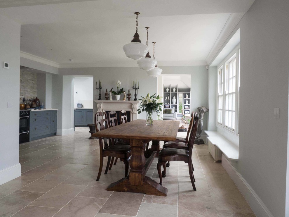 Photo of a large country kitchen/dining combo in Gloucestershire with grey walls, limestone floors, a standard fireplace and a stone fireplace surround.