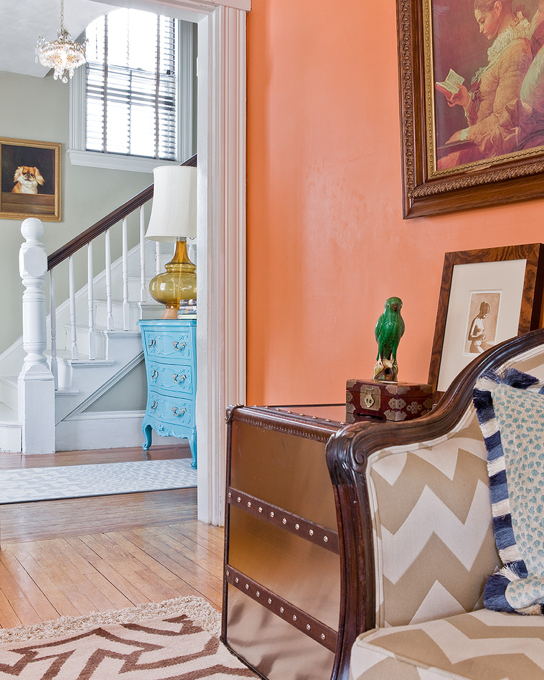 Design ideas for a mid-sized eclectic hallway in Boston with orange walls and light hardwood floors.