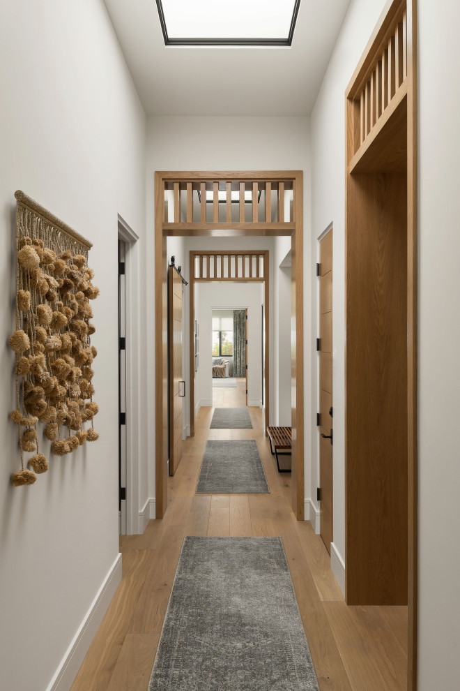 Modelo de recibidores y pasillos tradicionales renovados con paredes blancas, suelo de madera clara y suelo beige
