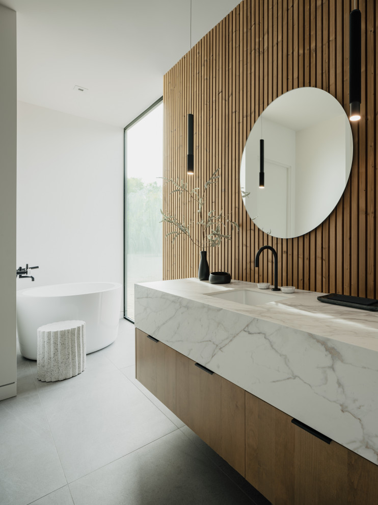 Modern inredning av ett badrum, med släta luckor, ett fristående badkar, en öppen dusch, vita väggar, ljust trägolv, ett undermonterad handfat och bänkskiva i kvarts