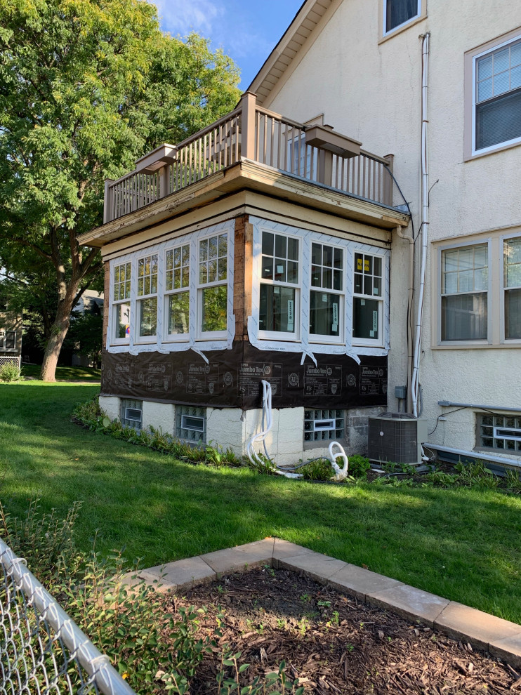 This is an example of a small traditional one-storey stucco beige house exterior in Minneapolis with a black roof.