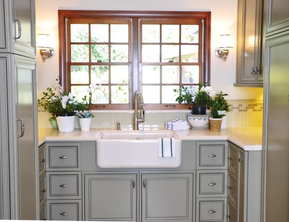 Design ideas for a mid-sized traditional u-shaped utility room in San Diego with recessed-panel cabinets, grey cabinets, limestone benchtops, white walls, travertine floors, a side-by-side washer and dryer, red floor and a farmhouse sink.