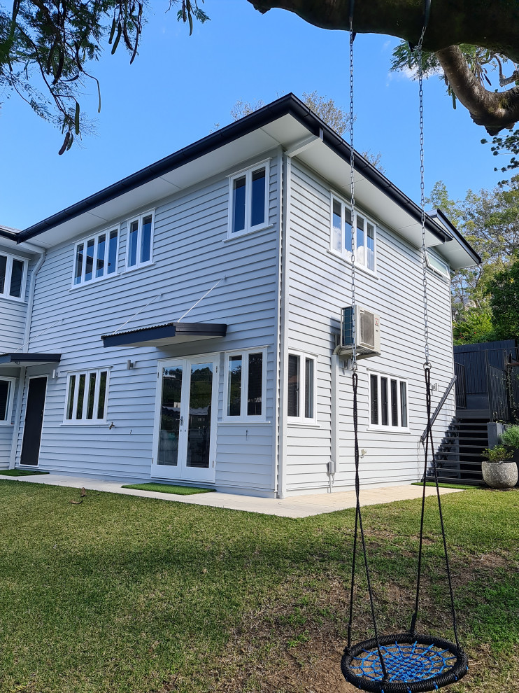 Large modern two-storey grey house exterior in Brisbane with wood siding, a hip roof and a metal roof.