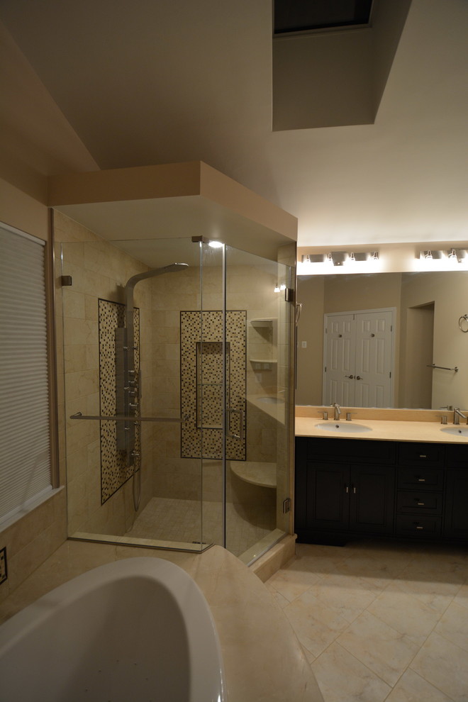Inspiration for a large transitional master beige tile and stone tile marble floor and beige floor drop-in bathtub remodel in Baltimore with dark wood cabinets, a two-piece toilet, beige walls, an undermount sink, beaded inset cabinets, solid surface countertops, a hinged shower door and beige countertops